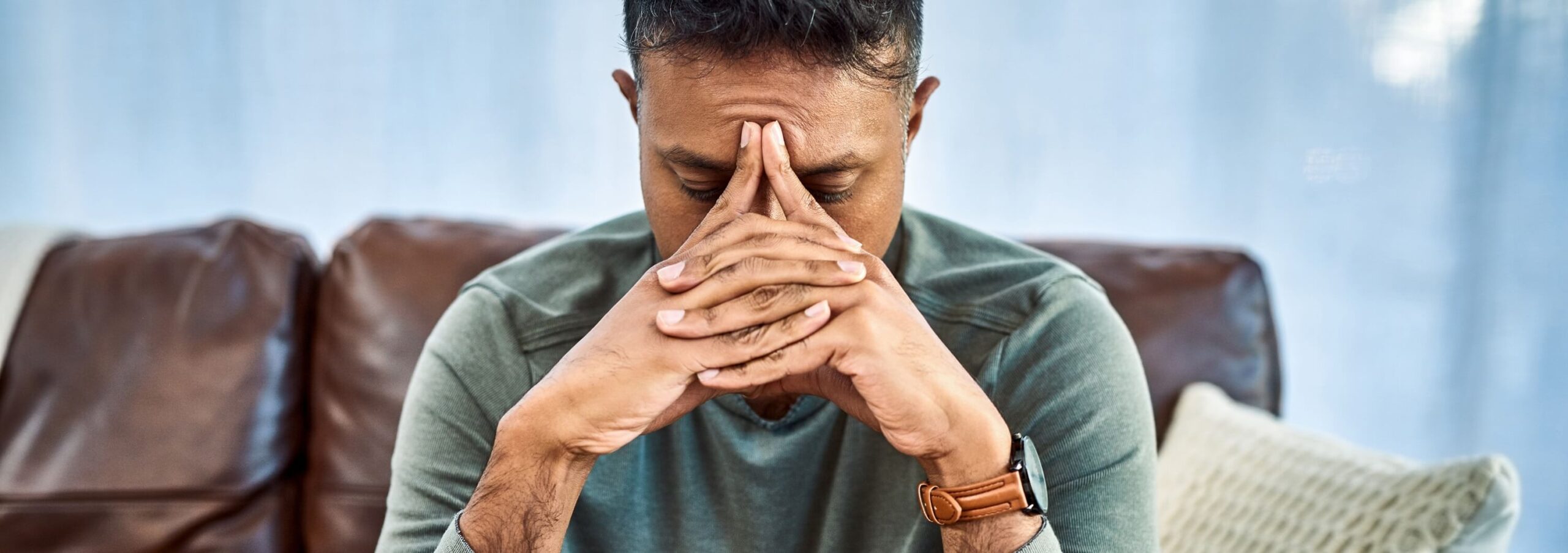 distressed male sitting with hands in front of face