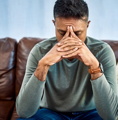 distressed male sitting with hands in front of face